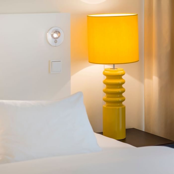 Table lamp beside a bed in a room at Falkensteiner Hotels & Residences
