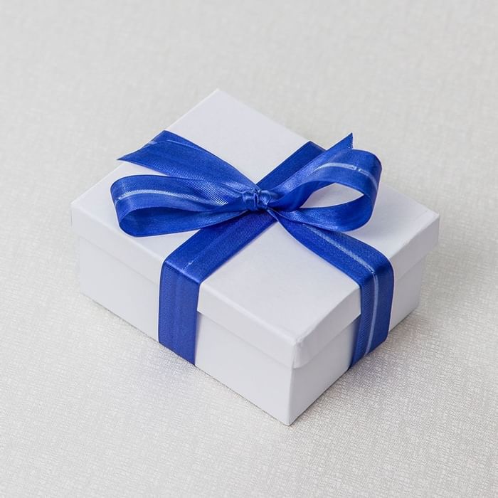 A gift box tied with a blue ribbon on a light background at Falkensteiner Hotels & Residences