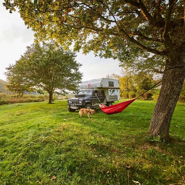 A truck with a camper parked under a tree with a red hammock at Falkensteiner Premium Camping Zadar