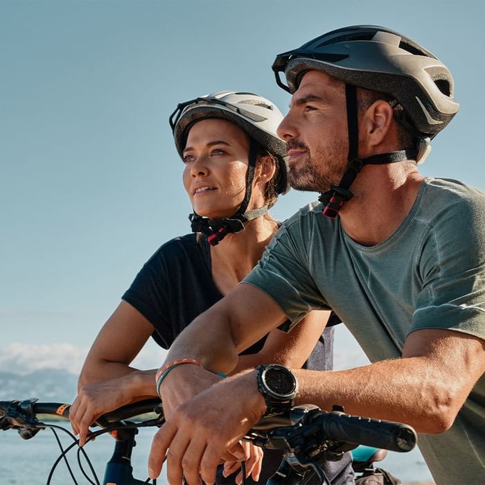 Two cyclists with bikes overlooking a scenic mountain view near Falkensteiner Hotels & Residences