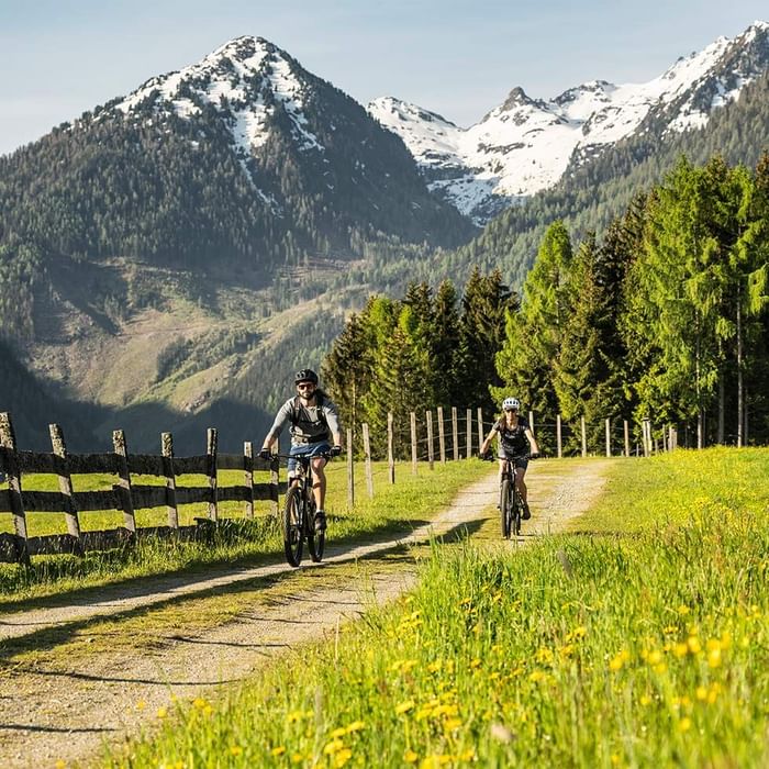 Two cyclists on a road amidst lush green hills at Falkensteiner Hotels & Residences