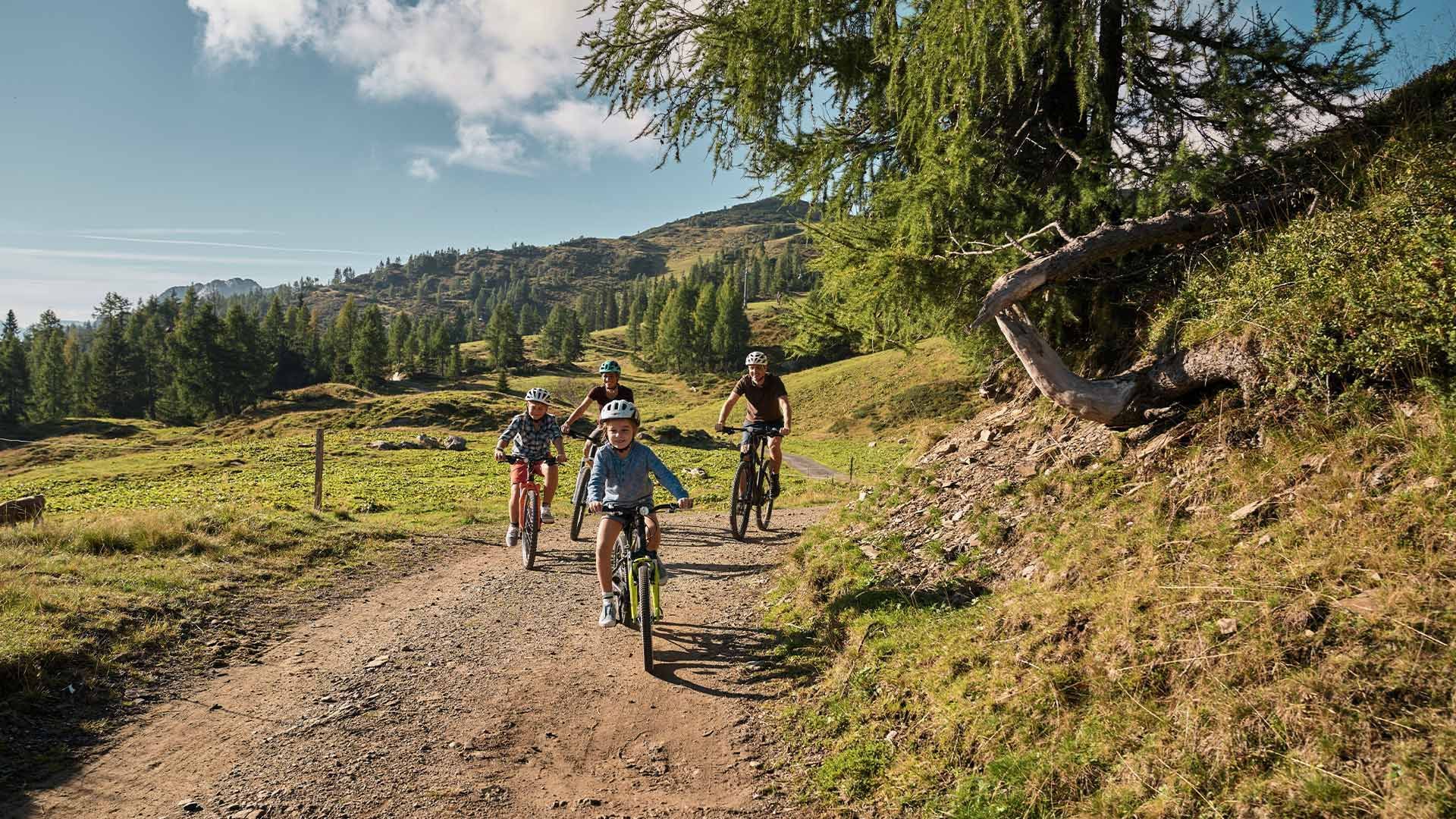 Cyclists on a dirt road amidst lush green hills at Falkensteiner Hotels & Residences