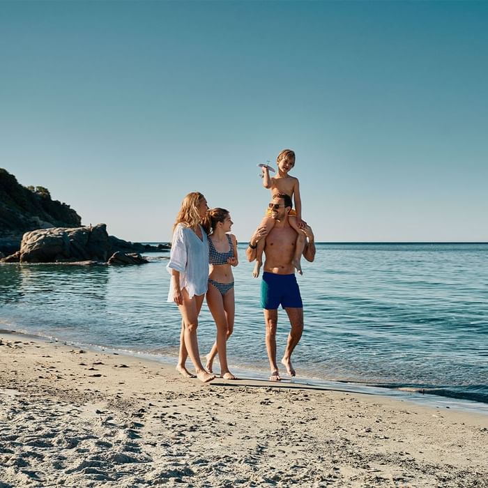Family walking on the beach near Falkensteiner Resort Capo Boi