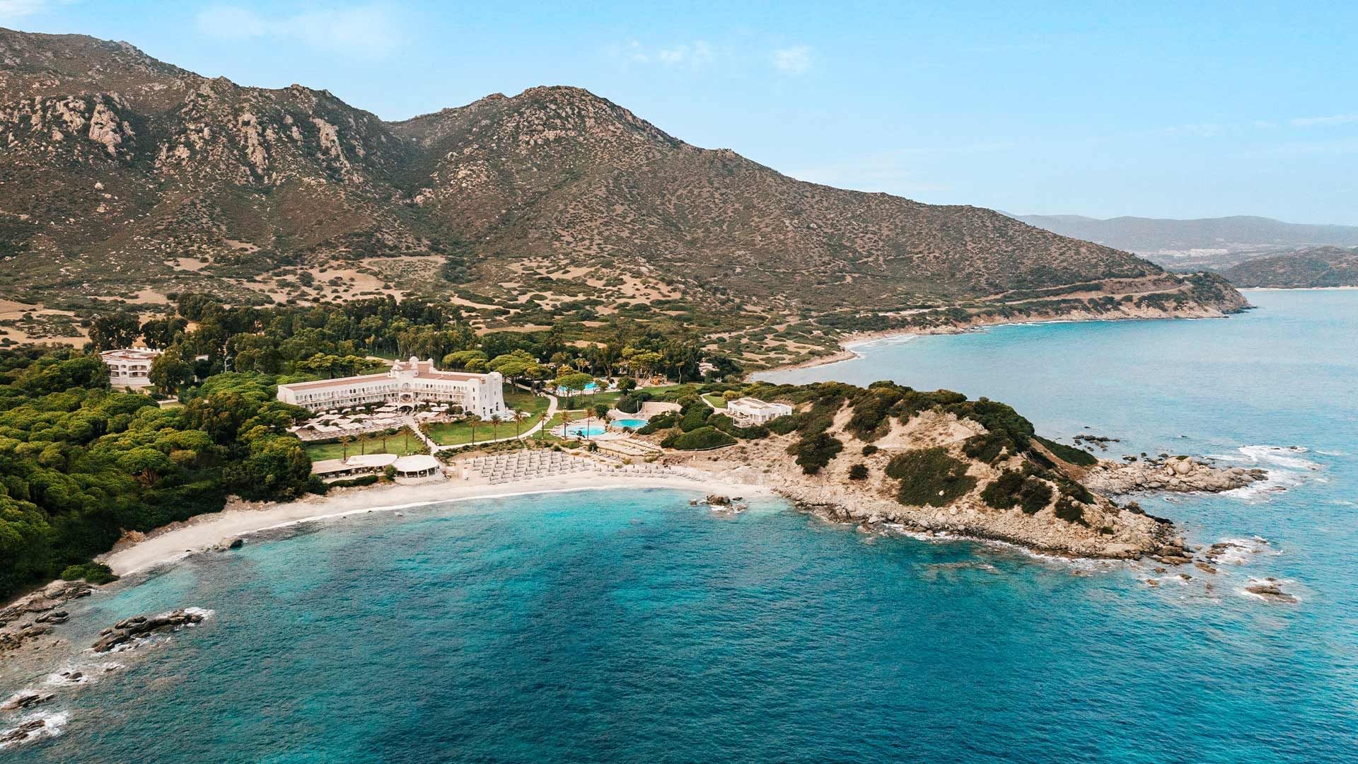 Zračni pogled na obalni hotel okružen planinama i plavim morem.
