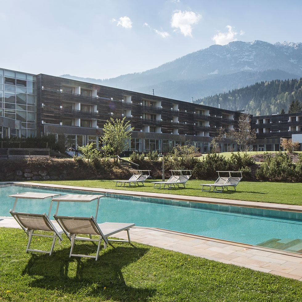 Outdoor pool area with sun beds at Falkensteiner Hotel & Spa Carinzia