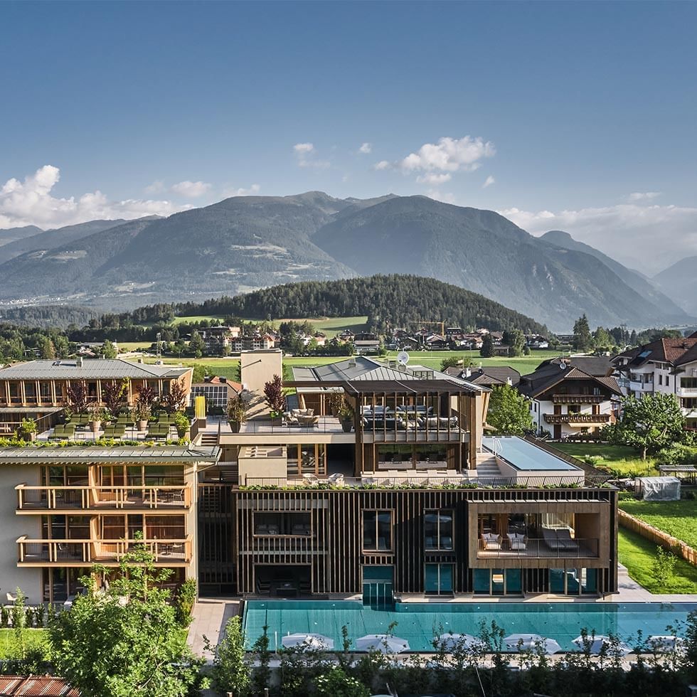 Aerial view of the hotel with pool in front of mountain landscape at Falkensteiner Hotel Kronplatz