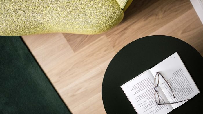 Close-up top view of the wooden table with a book and a glass at Falkensteiner Hotels & Residences