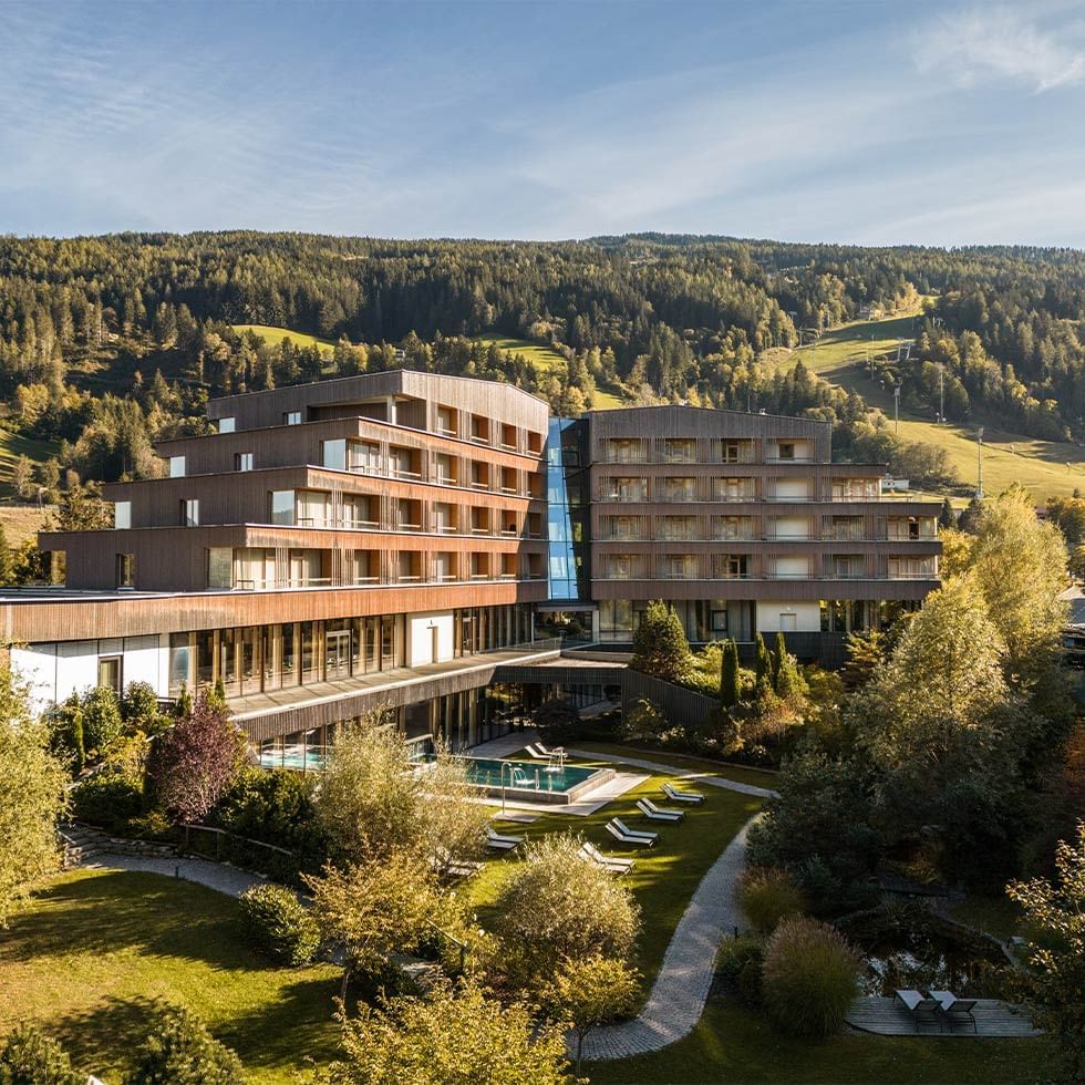 Modern hotel exterior surrounded by green lawns with rolling hills at Falkensteiner Hotel Schladming