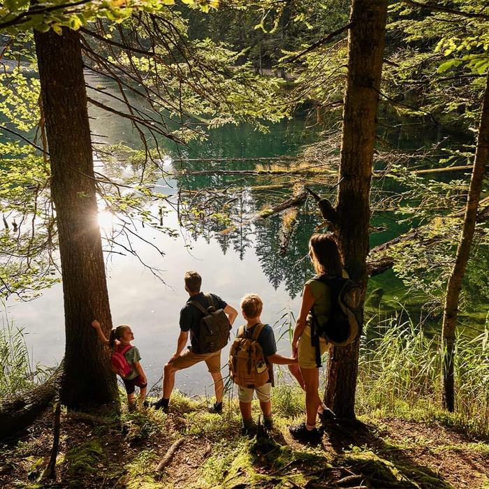 Eine Familie mit zwei Kindern steht an einem See und genießt den Ausblick.