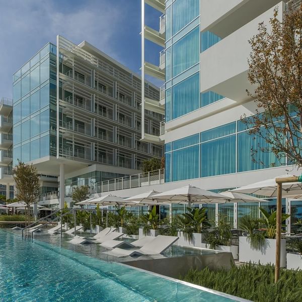 Angle view of the hotel exterior with pool and sunbeds at Falkensteiner Hotel & Spa Jesolo