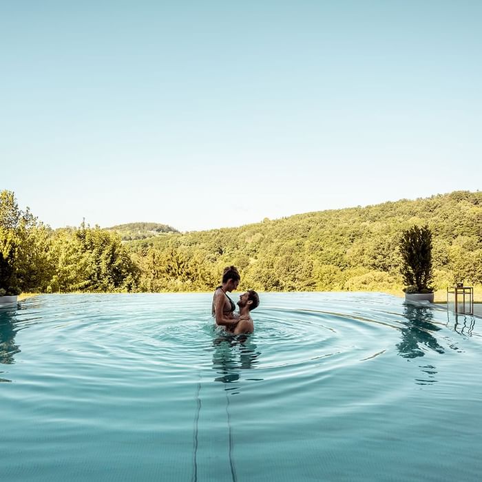 A couple enjoying the outdoor pool at Falkensteiner Hotels & Residences