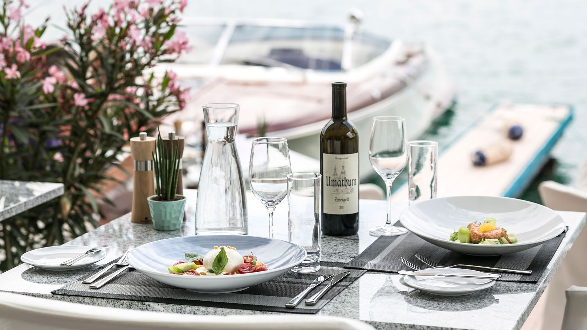 Close-up of dishes served with wine in a table at Falkensteiner Hotels & Residences