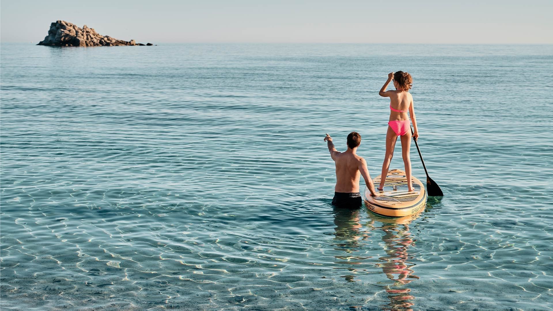 Father and kid paddleboarding on the Beach at sundown near Falkensteiner Hotels & Residences
