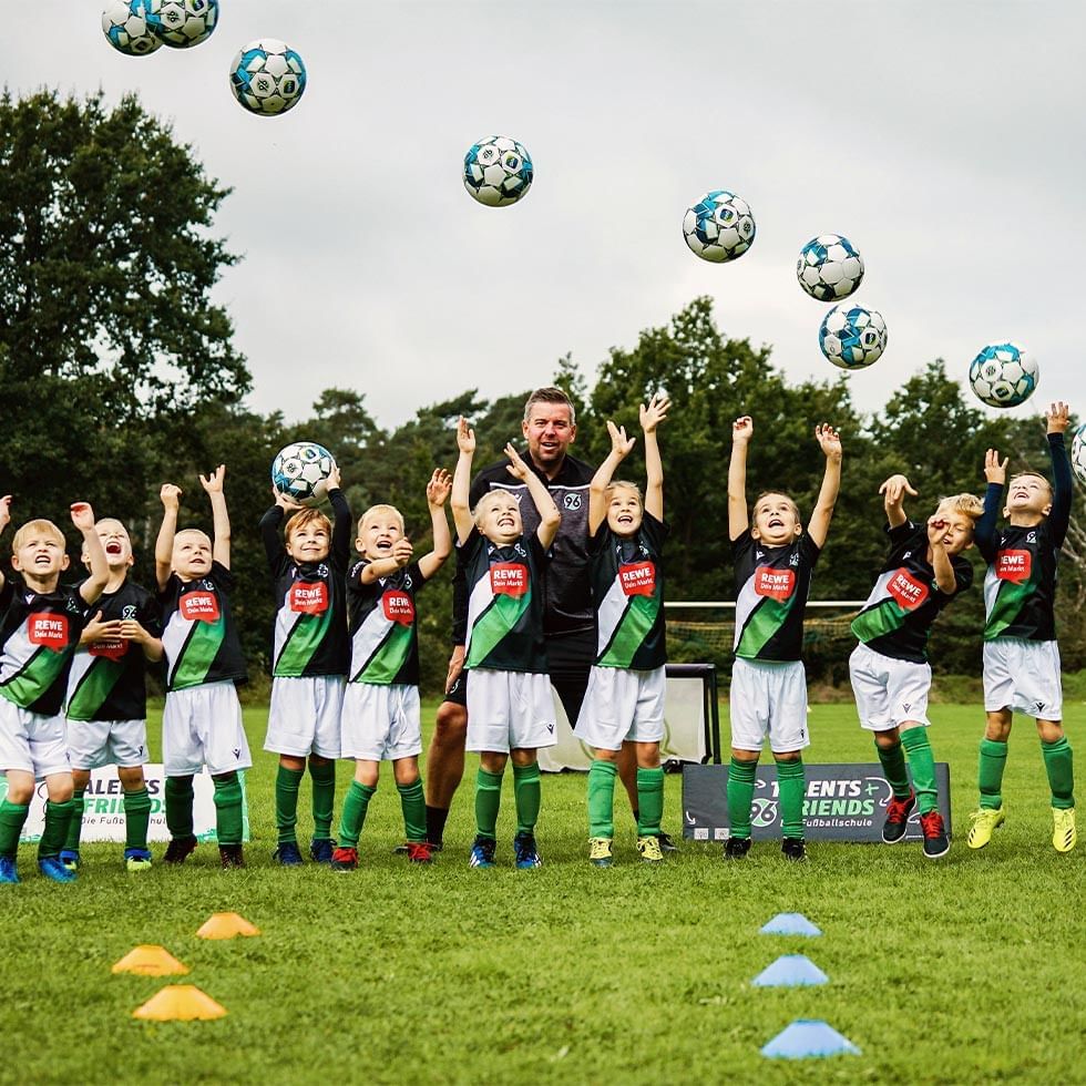 Coach and kid soccer players tossing balls in the air at Falkensteiner Hotels & Residences