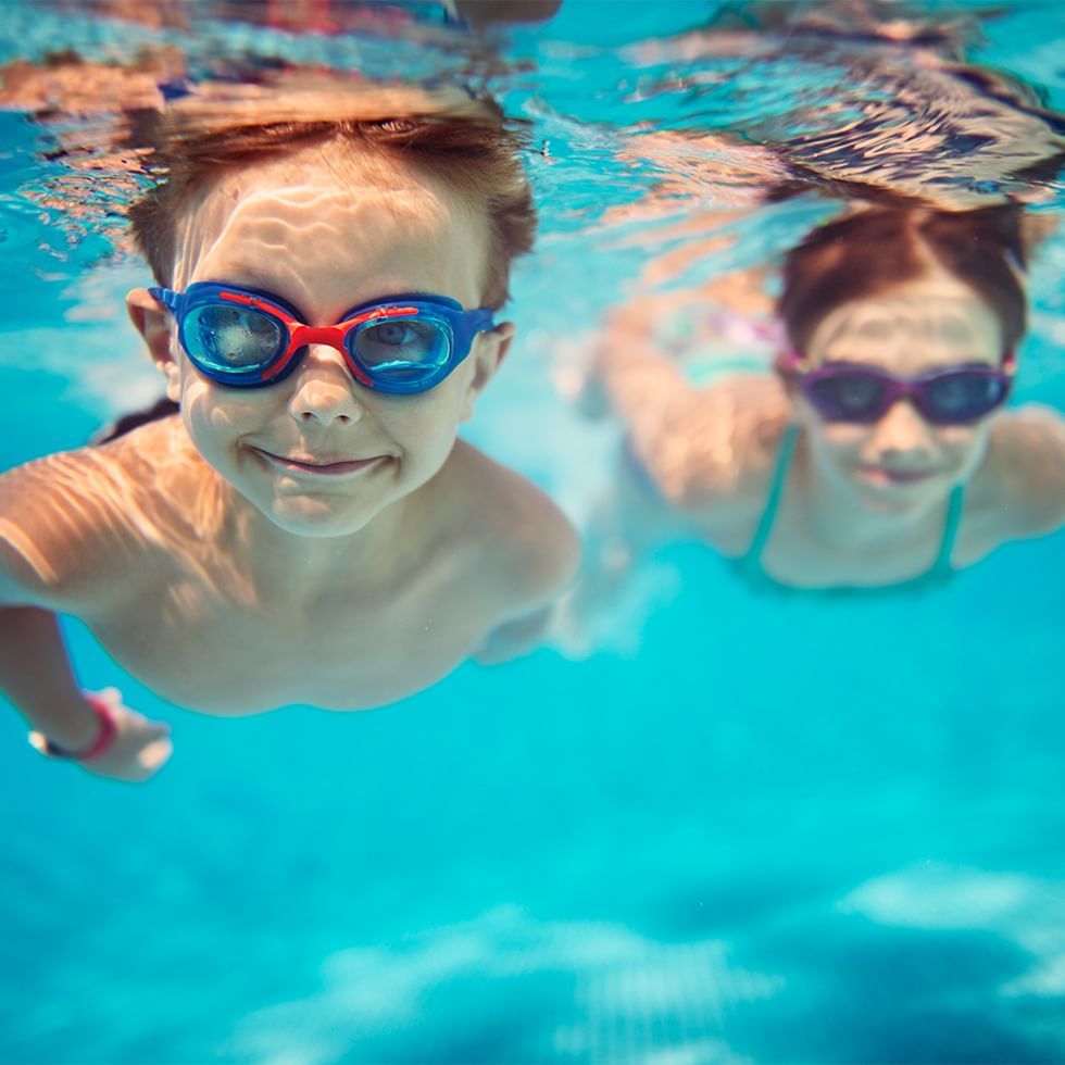 Two kids with goggles in underwater in a pool at Falkensteiner Hotels & Residences