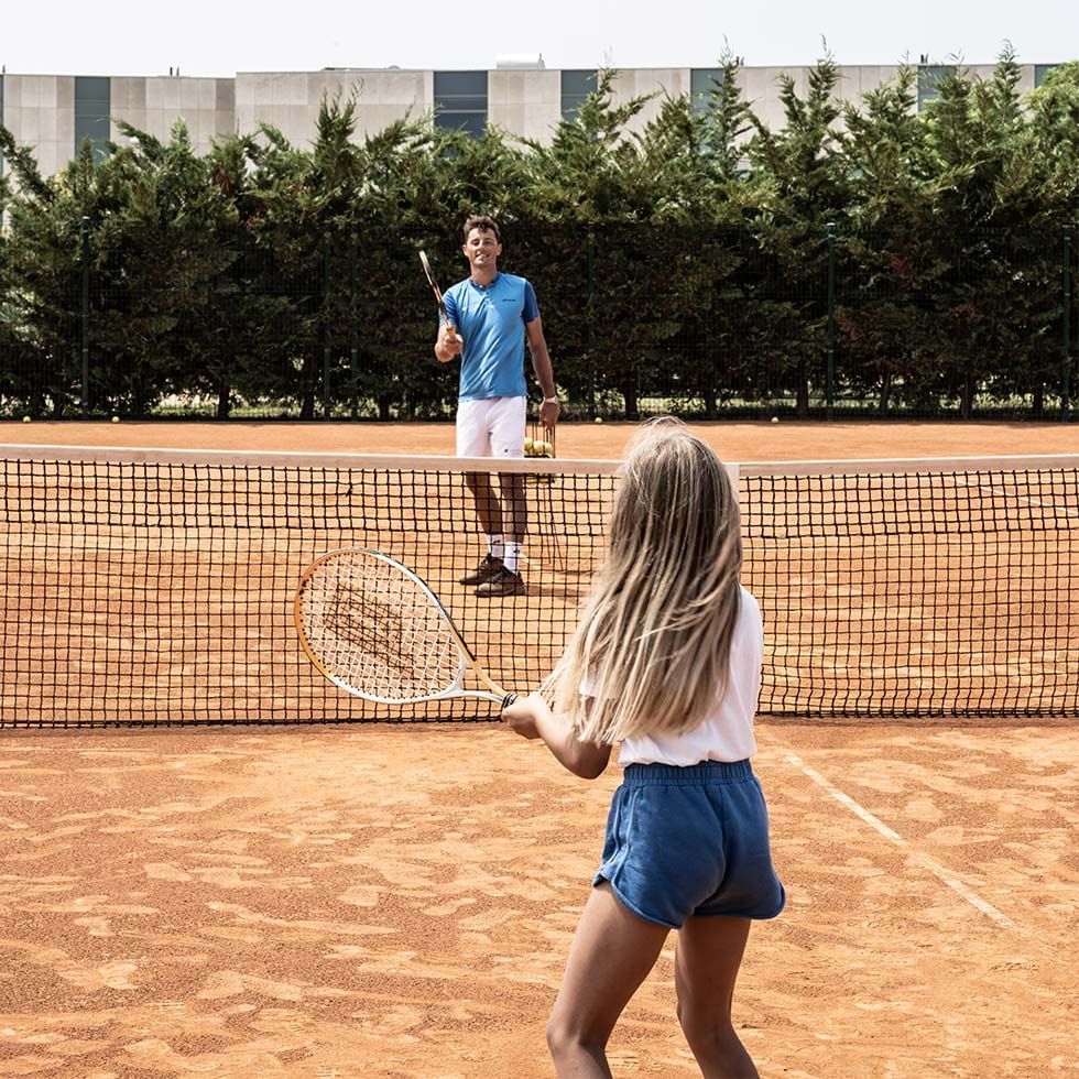 Daughter & father playing tennis on a clay court at Falkensteiner Hotels & Residences