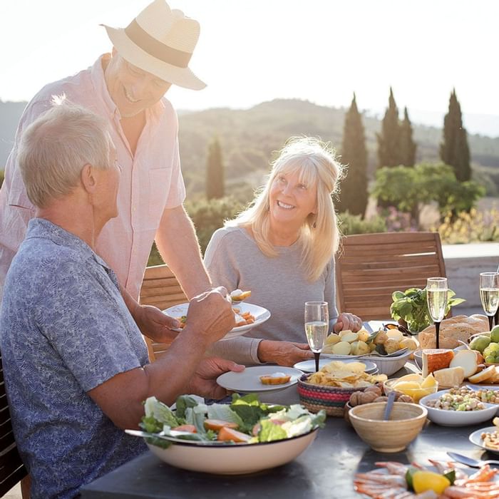Group of seniors having lunch on a table outdoors at Falkensteiner Hotels & Residences
