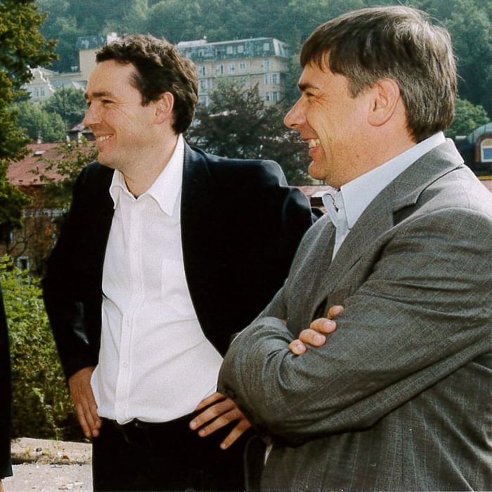 Two men in suits standing with crossed arms at Falkensteiner Hotels & Residences