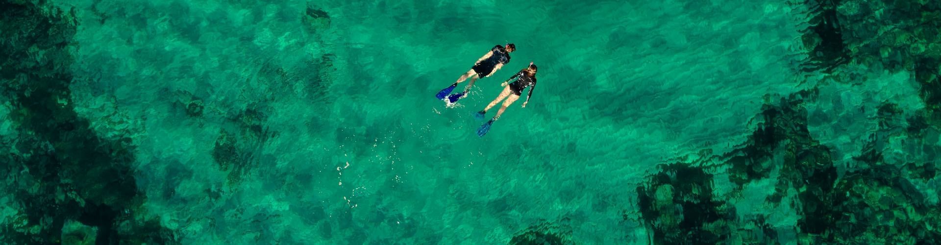 Aerial view of two swimmers swimming in the lake near Falkensteiner Hotels & Residences