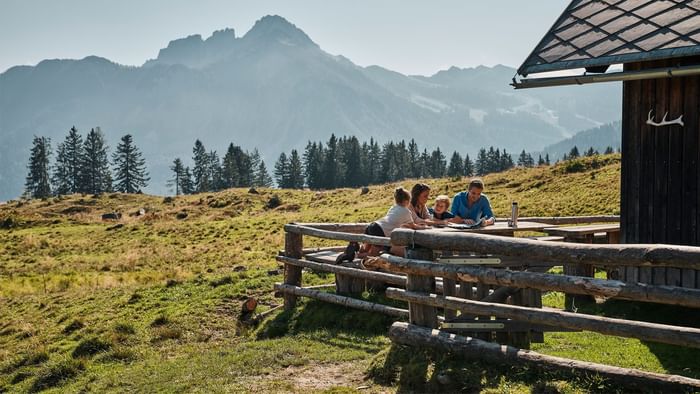 Distant view of a family at the garden of a wooden cottage near Falkensteiner Hotels & Residences