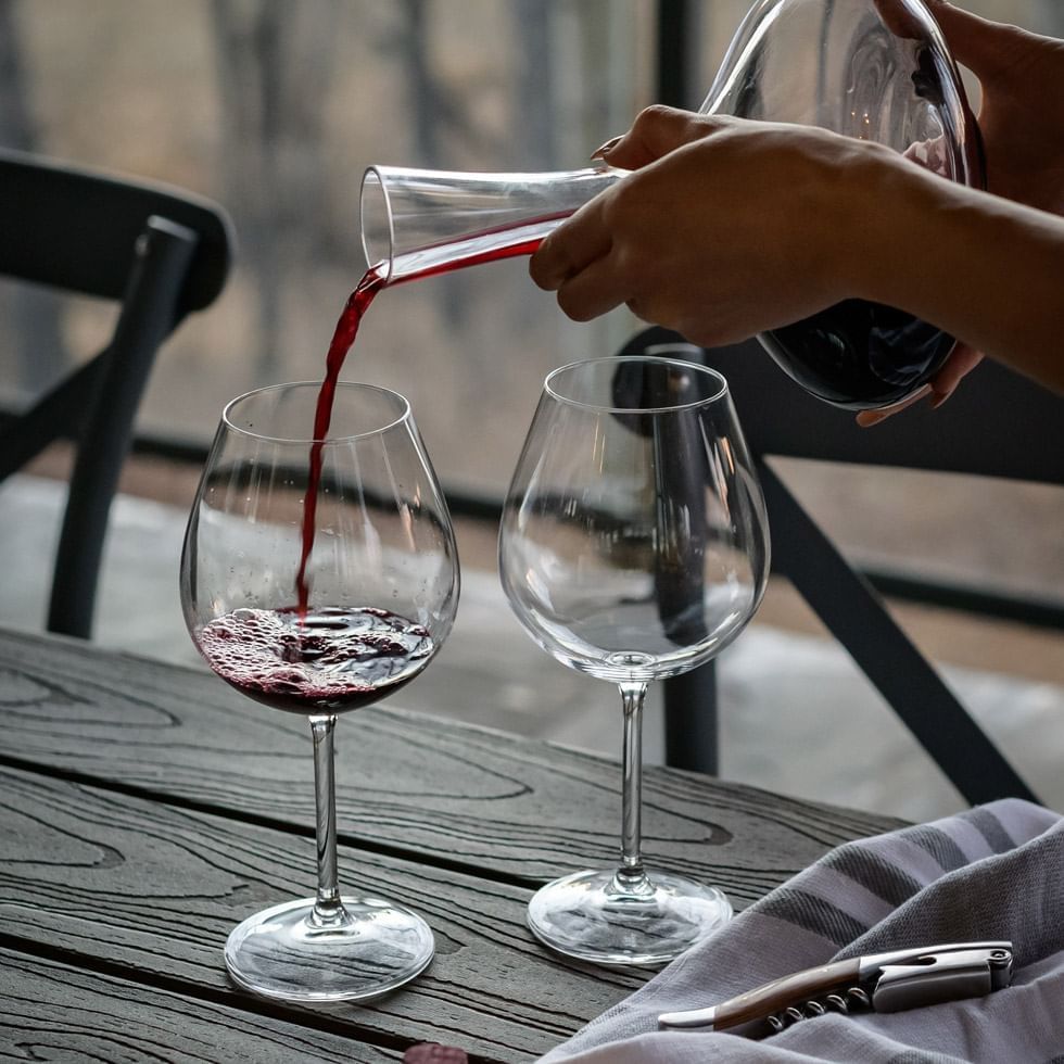 Close-up of a women poring red wine to glasses on the table at Falkensteiner Hotels & Residences