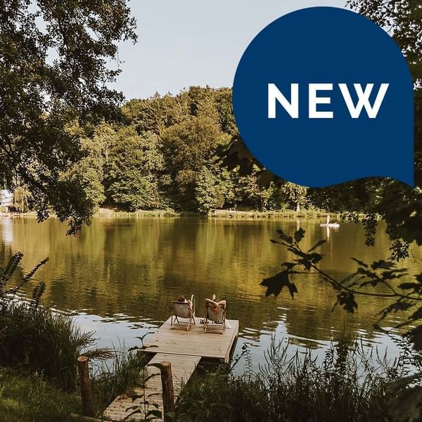 'NEW' labeled poster with serene lakeside with a wooden dock at Falkensteiner Hotels & Residences