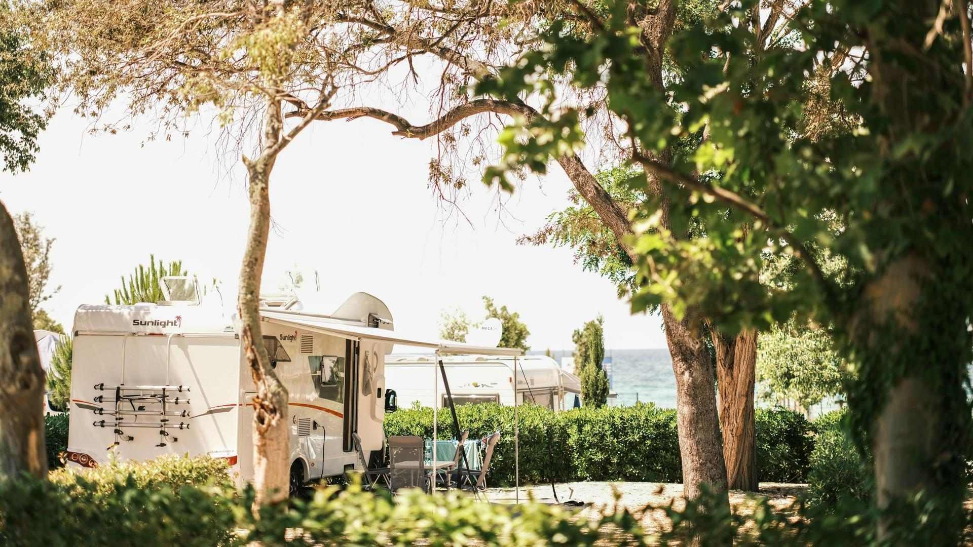 Two campers nestled among trees with a view of the sea at Falkensteiner Premium Camping Zadar