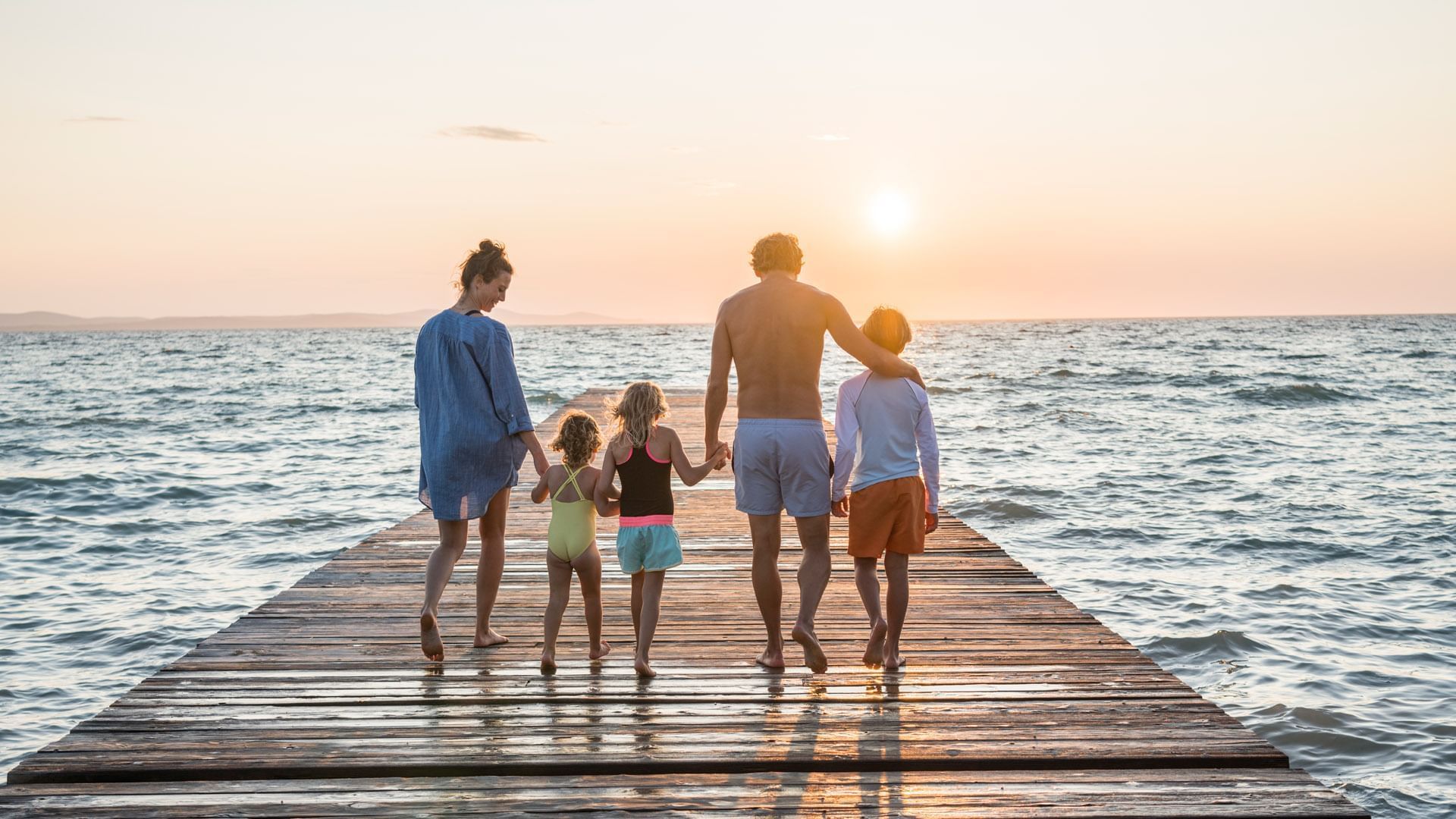 Family walking on a jetty by the sea near Falkensteiner Hotels & Residences