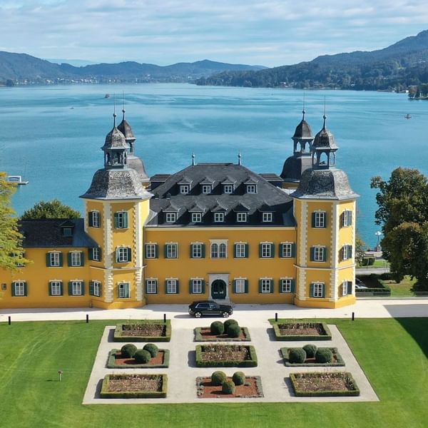 Exterior view of Falkensteiner Schlosshotel Velden with landscaped gardens by a blue lake