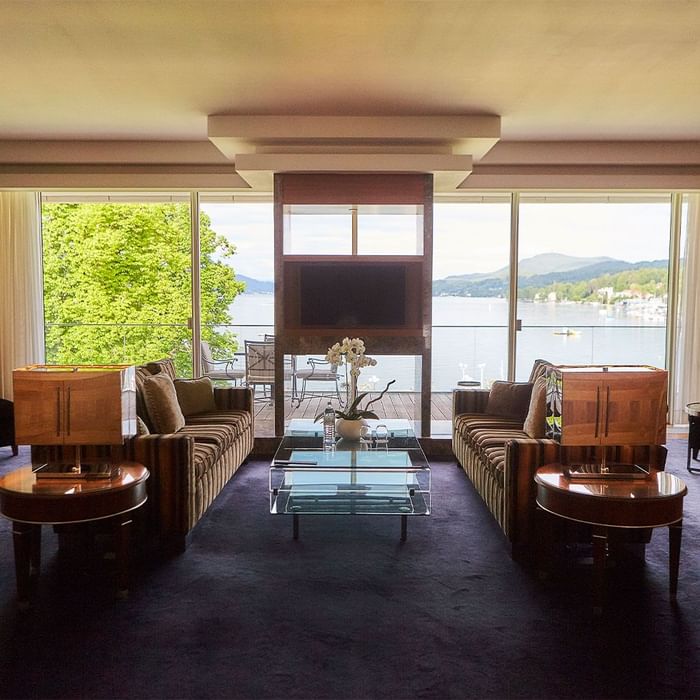 Elegantes Wohnzimmer mit Panoramablick auf See und Berge, gefüllt mit modernen Möbeln und Kunst.