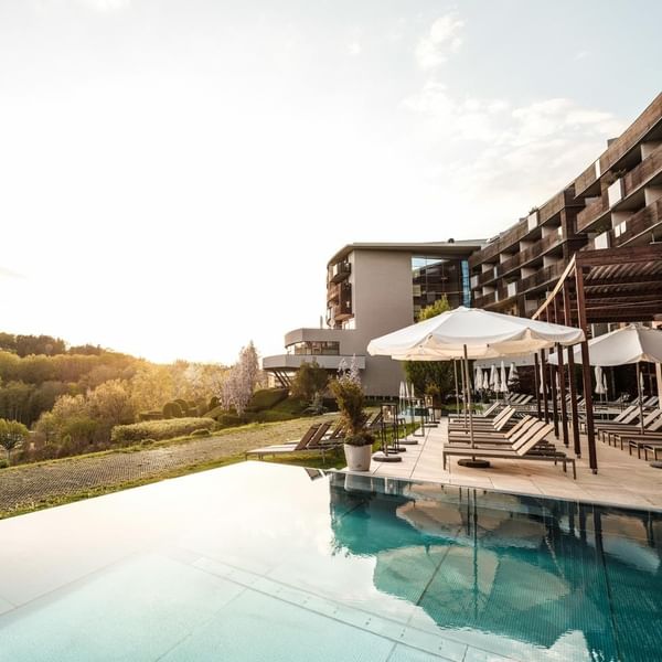 Sunbeds lined by the outdoor pool area at Falkensteiner Balance Resort Stegersbach